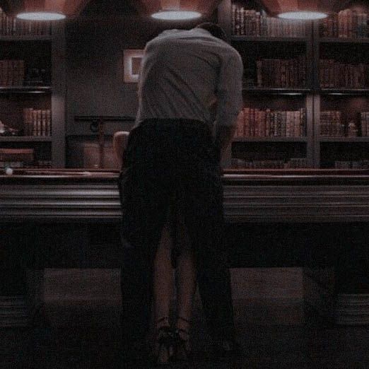 a man and woman standing in front of a bookshelf