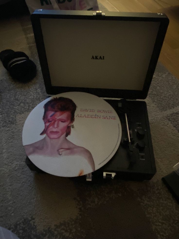 a record player sitting on top of a table next to a box with an image of a woman's face