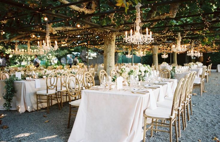 an outdoor dining area with tables, chairs and chandeliers