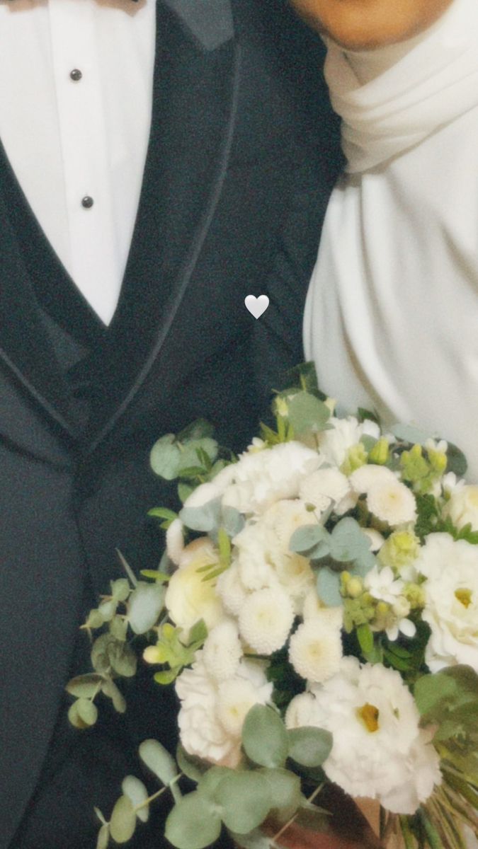 two people dressed in tuxedos and bow ties posing for a photo with flowers