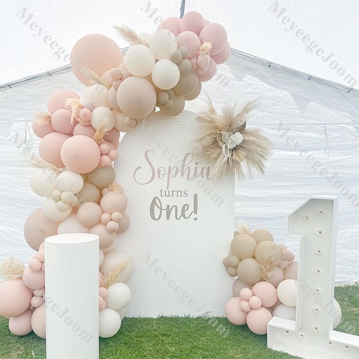 a white and pink balloon arch with balloons on the top is set up in front of a tent