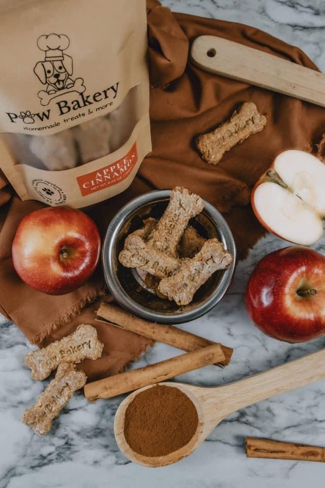 an assortment of dog treats on a marble counter with apples, cinnamon sticks and apple slices