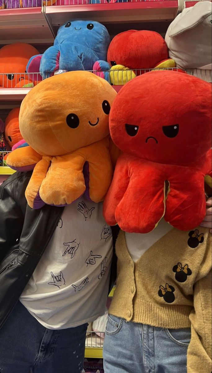 two people standing next to each other with stuffed animals on their shoulders in a store