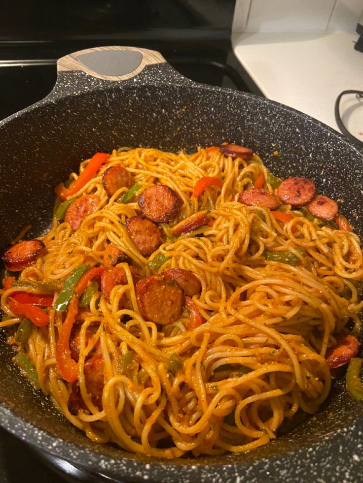 a skillet filled with spaghetti and sausage