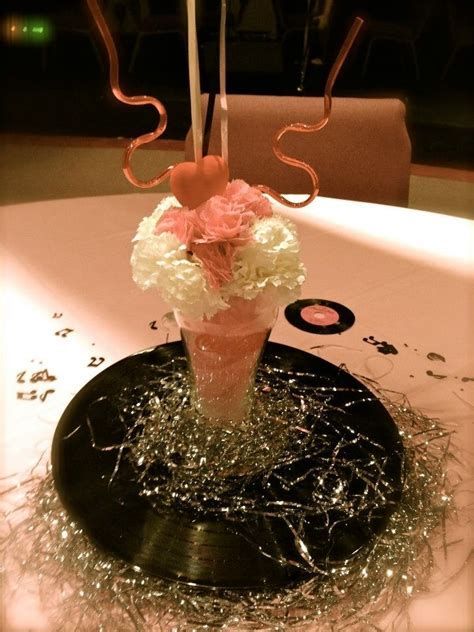 a vase filled with white and pink flowers on top of a black tablecloth covered table