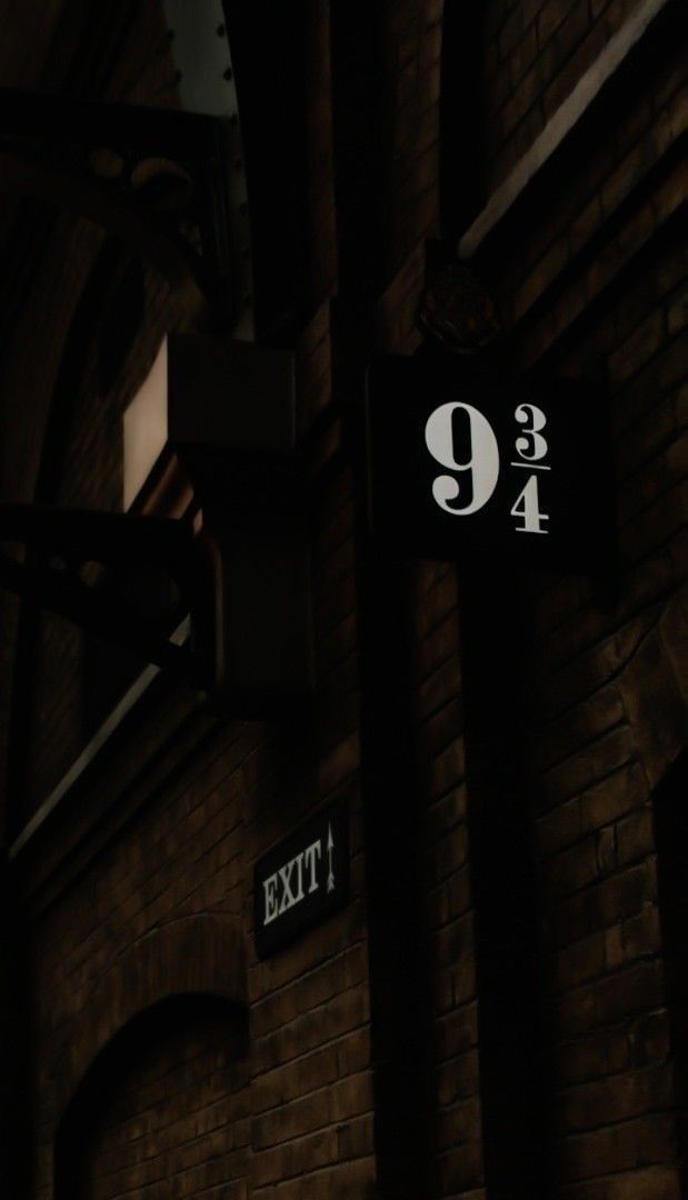 an exit sign on the side of a brick building at night with light coming through