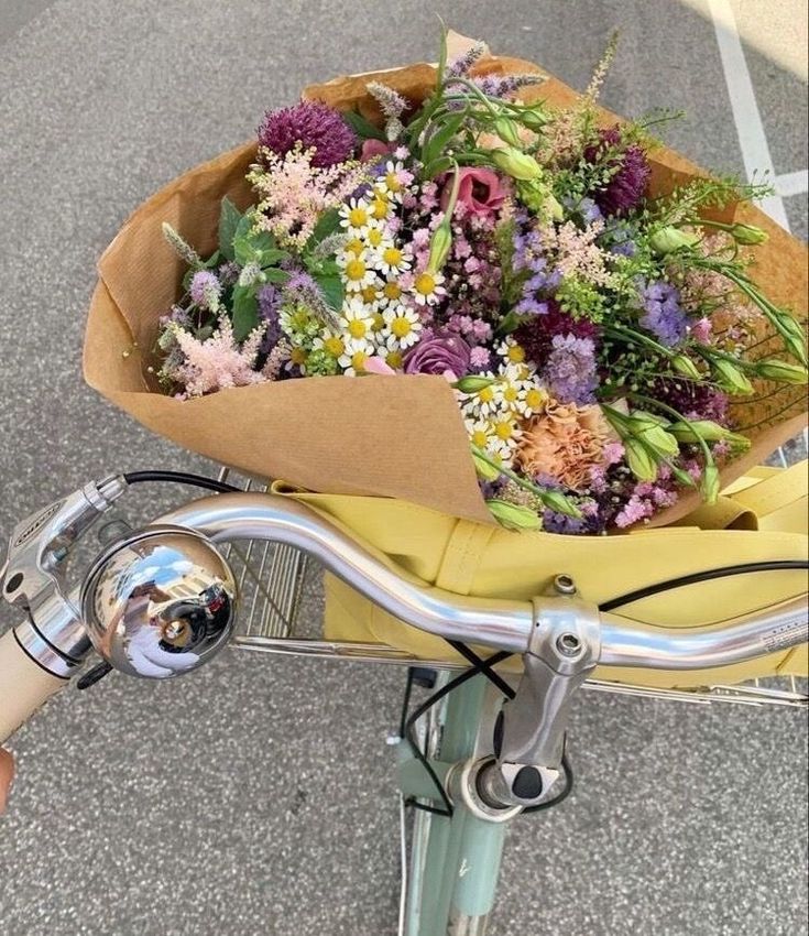 a bouquet of flowers sitting on the handlebars of a bicycle