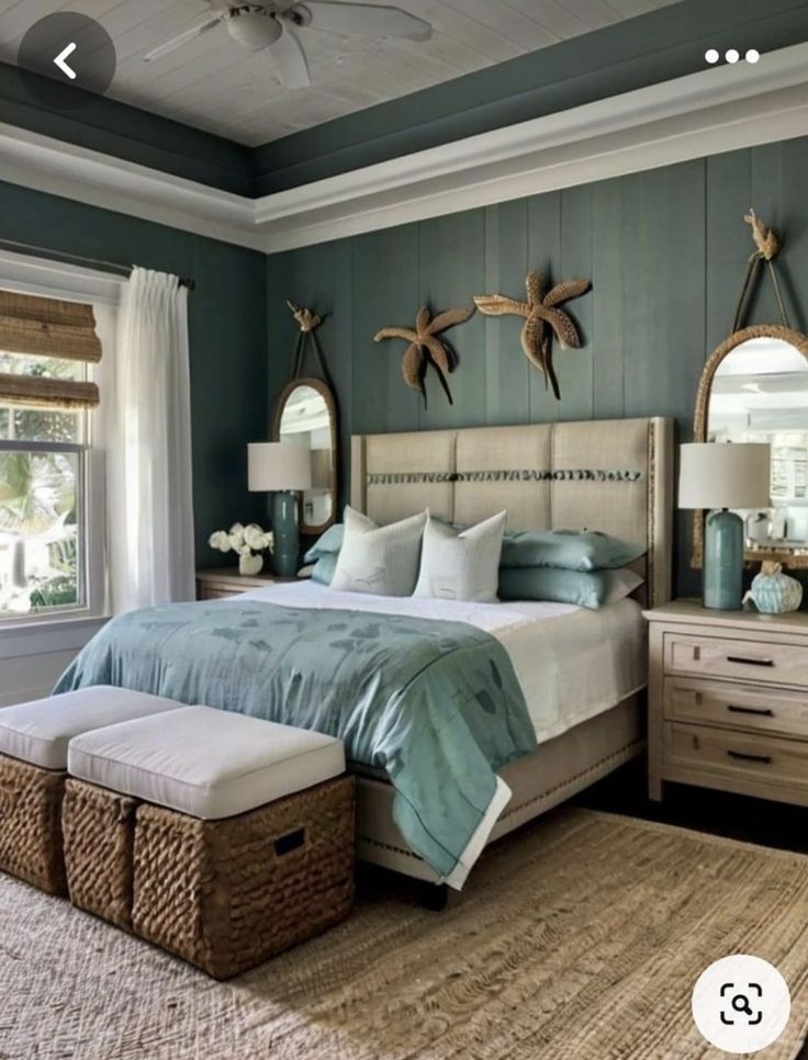 a bed room with a neatly made bed and two mirrors on the wall above it