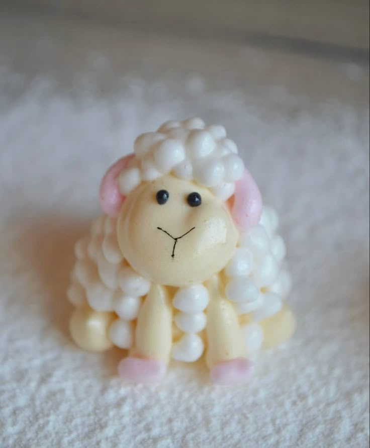 a small toy sheep sitting on top of a white blanket