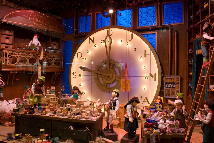 a large clock in the middle of a room filled with dolls and other things on display