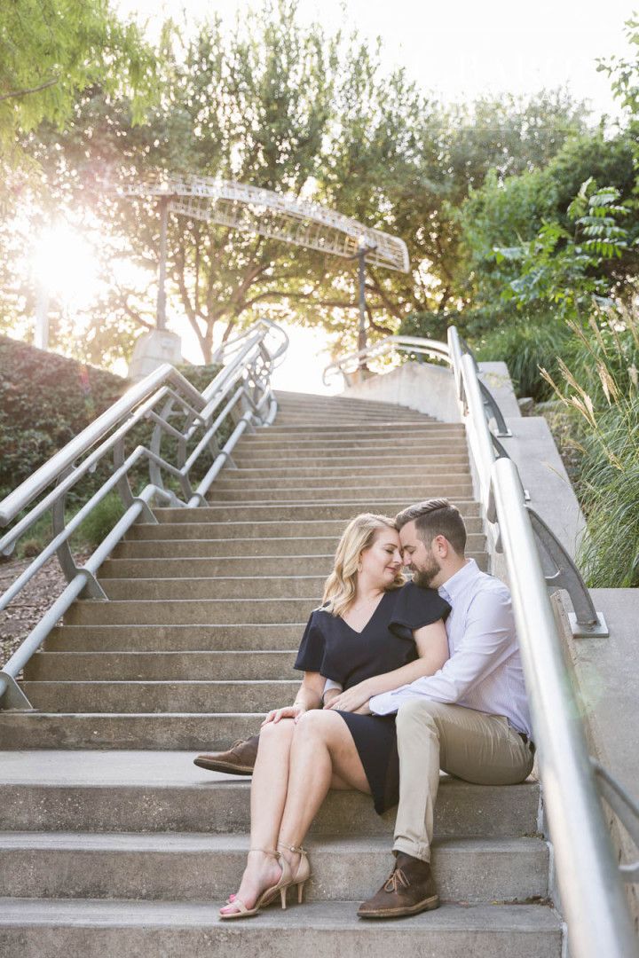 a man and woman sitting on the steps in front of stairs with their arms around each other