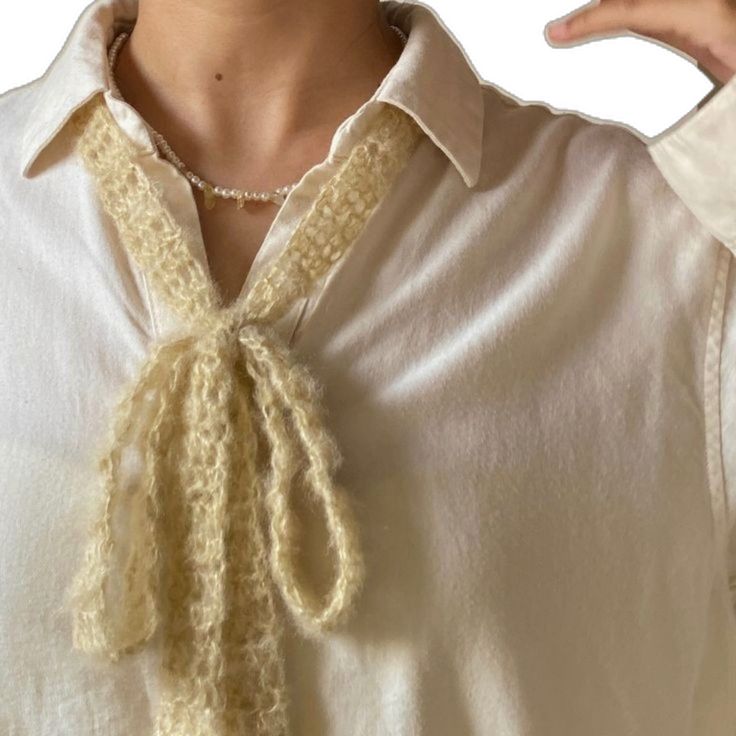 a woman wearing a white shirt with a crochet tie around her neck and collar