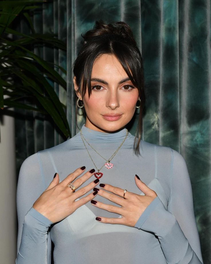 a woman with her hands on her chest wearing rings and holding onto the top of her shirt