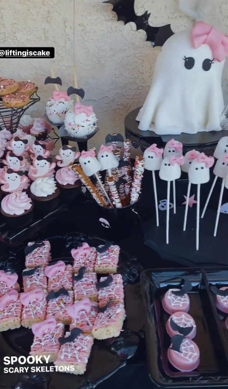 a table topped with lots of cupcakes covered in pink frosting