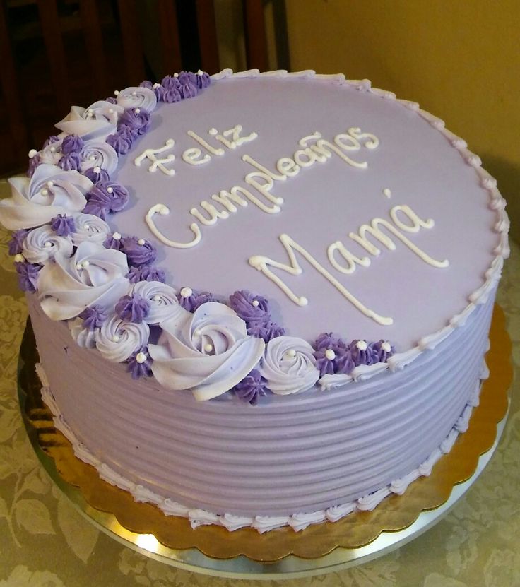 a purple cake with white frosting and flowers on the top is sitting on a table