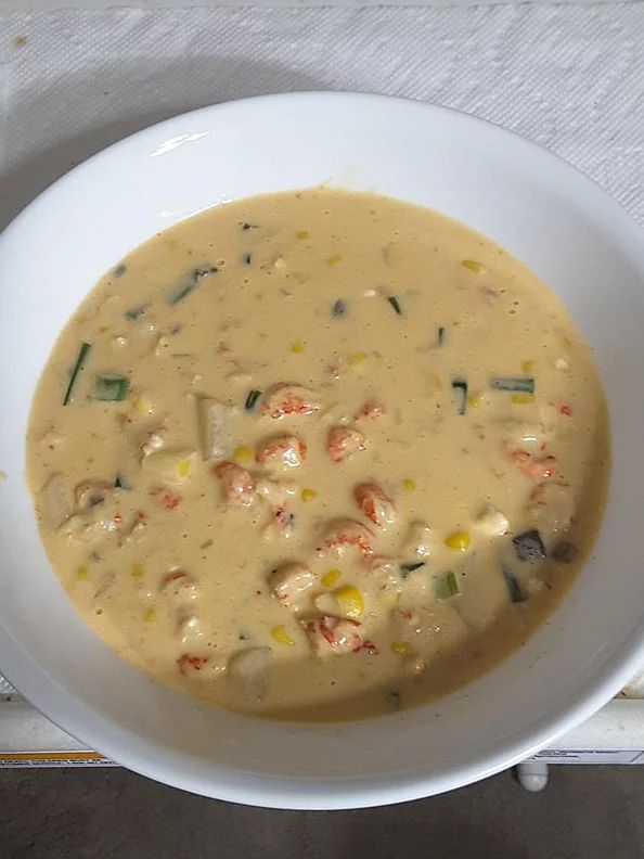 a white bowl filled with soup sitting on top of a table next to a napkin