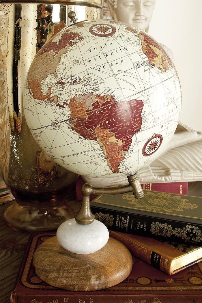 a globe sitting on top of a wooden table next to two books and a statue