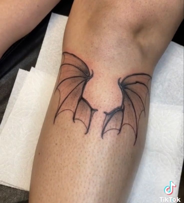 a tattoo on the leg of a person with a black dragon design on it's arm