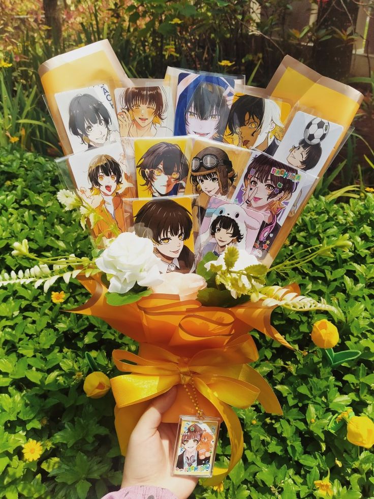 someone holding up some cards with pictures on them in front of green bushes and flowers