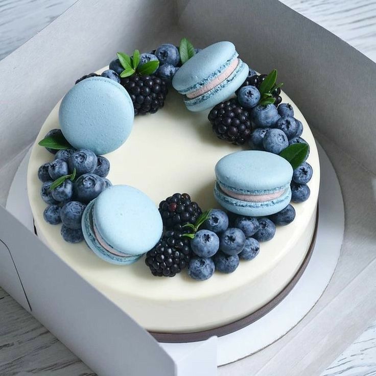 a cake decorated with macaroons, blueberries and blackberries in a box