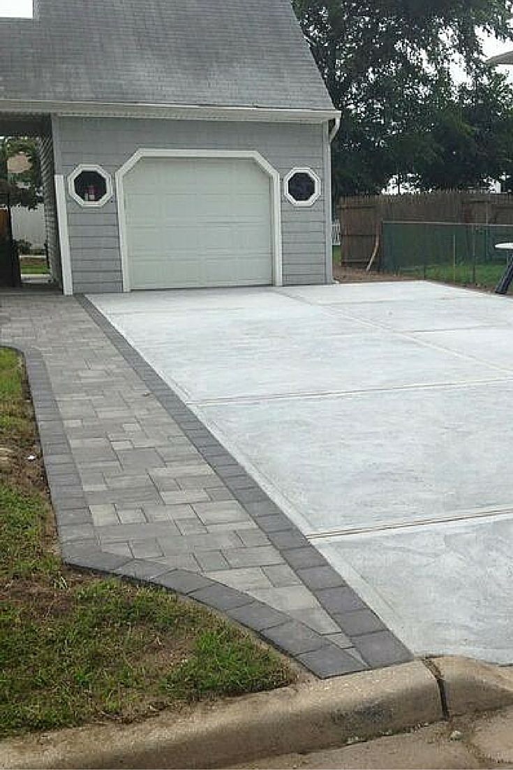 a fire hydrant sitting in the middle of a driveway next to a house with a garage