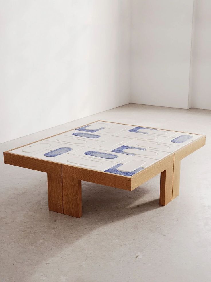 a coffee table with blue and white designs on the top, sitting in an empty room