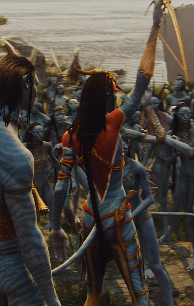 two people dressed as avatars in front of the ocean with swords and armor on