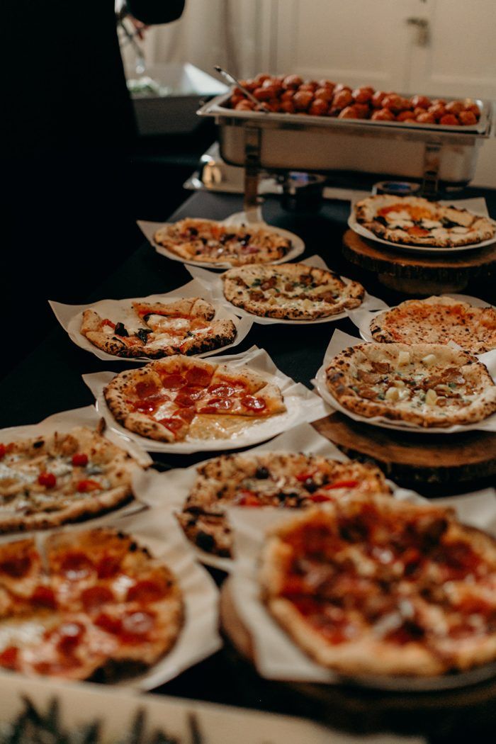 many different types of pizzas are on the table with other dishes in the background