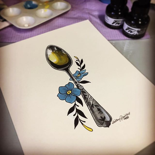 a spoon with flowers on it sitting next to some paint