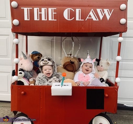 there are many stuffed animals sitting in the red wagon that says the claw on it