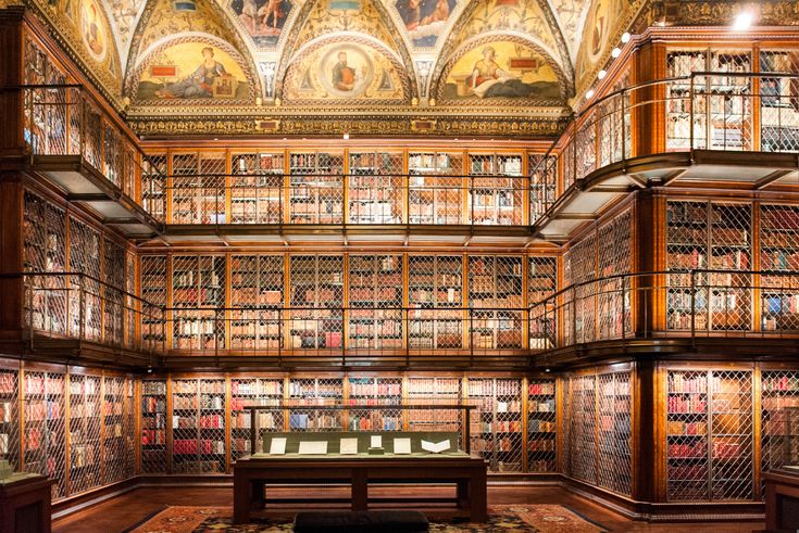 the library has many bookshelves and paintings on the walls, along with a bench