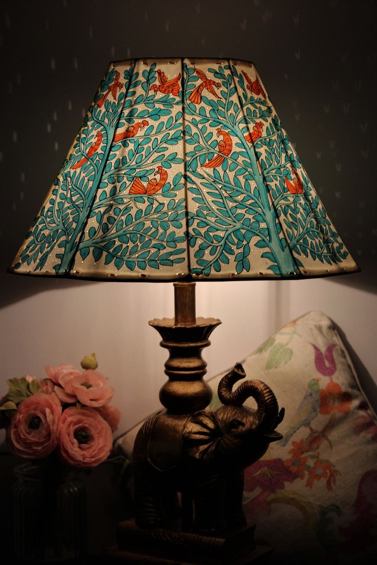 an elephant lamp sitting on top of a table next to a flowered vase and pillow