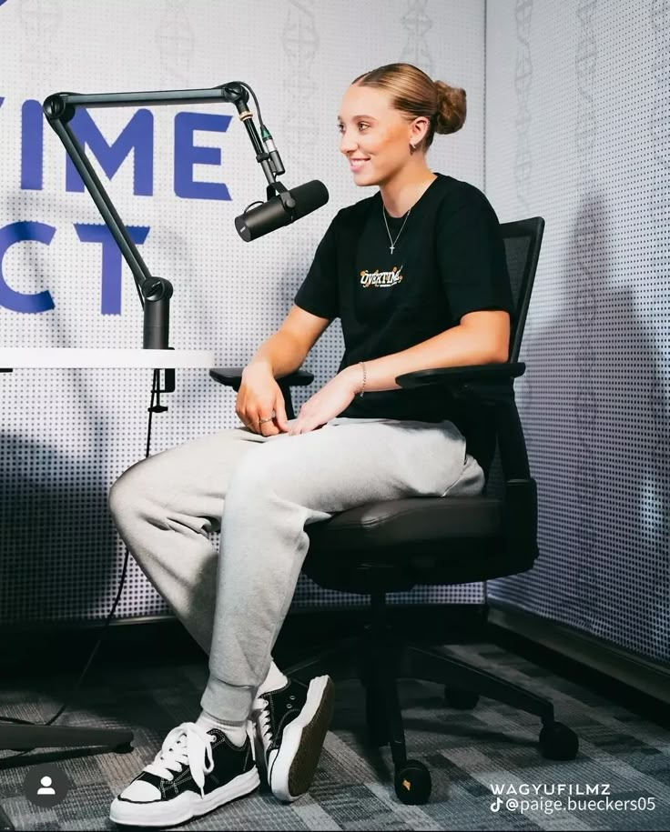 a woman sitting in front of a microphone on top of a chair next to a microphone