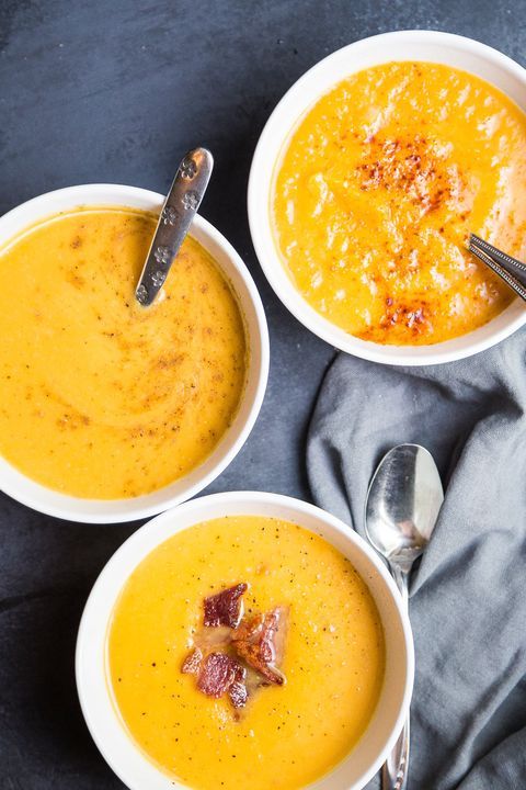 three bowls filled with soup on top of a blue table cloth next to silver spoons