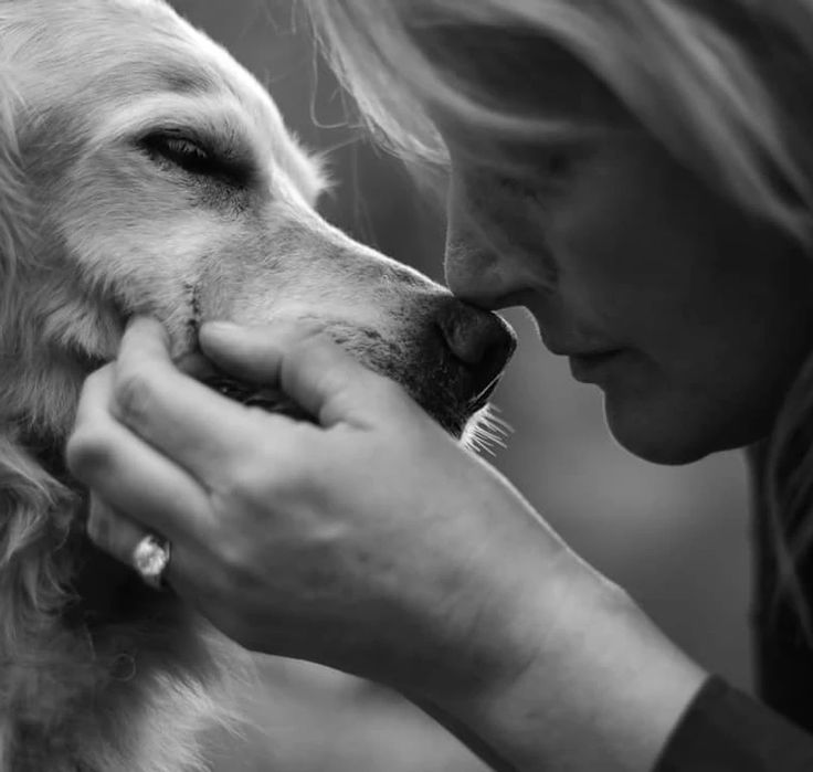 a woman is petting a dog with her nose close to the camera, black and white photo