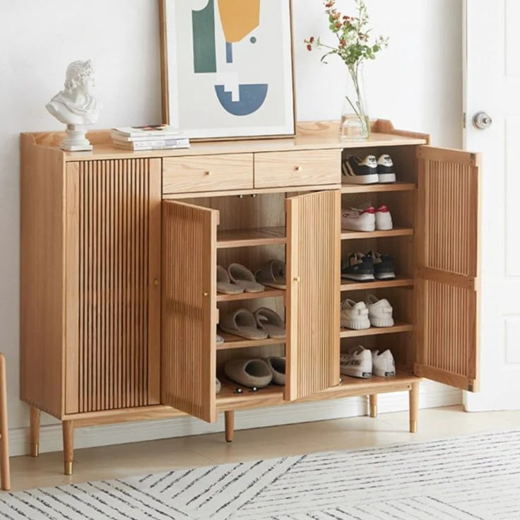 a wooden cabinet with shoes on it in front of a white wall and a painting