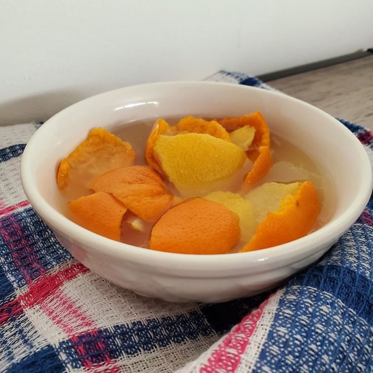 a white bowl filled with orange peels on top of a checkered table cloth