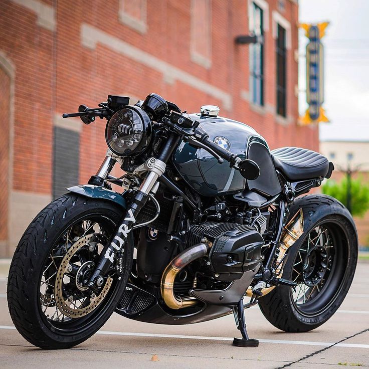 a black motorcycle parked in front of a red brick building with gold accents on it