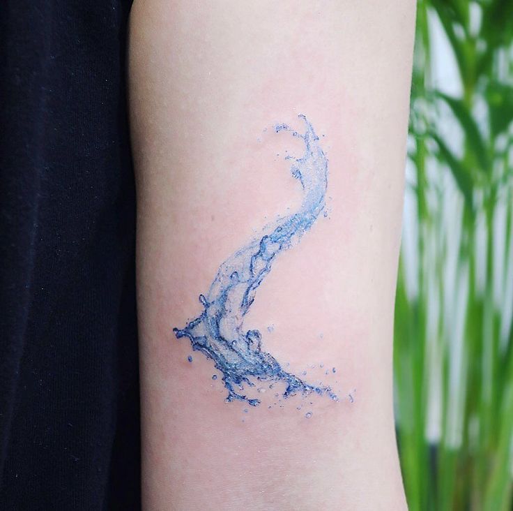 a blue ink tattoo on the arm of a woman's left arm, with water splashing from it