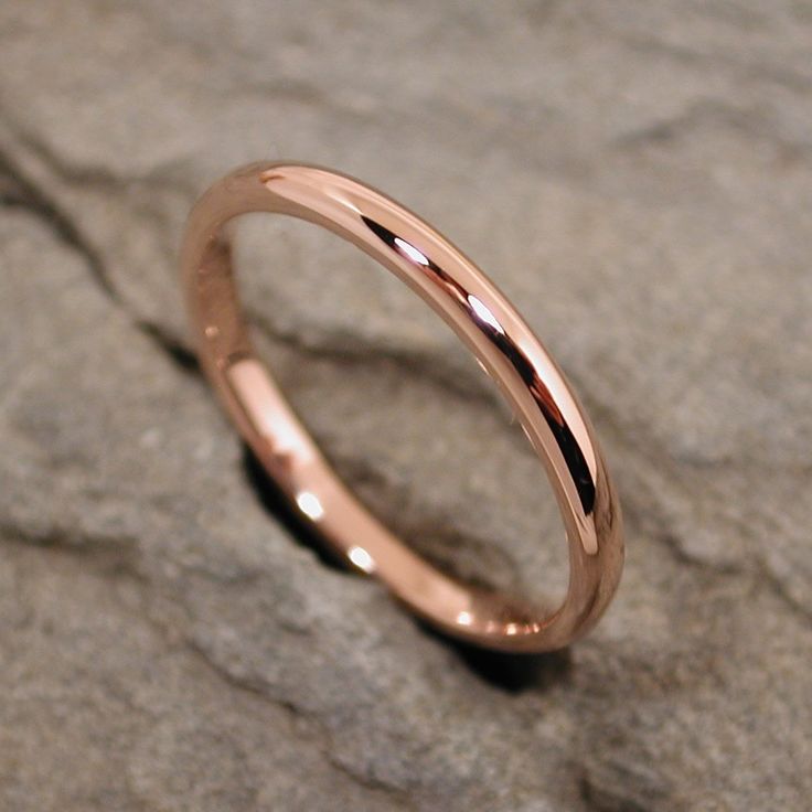 a rose gold wedding ring sitting on top of a rock