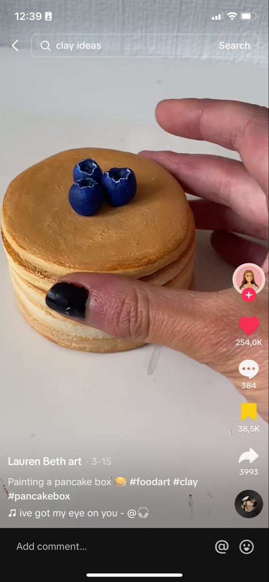 a person's hand is holding a cookie with blue decorations on it, and there are two other items in the background