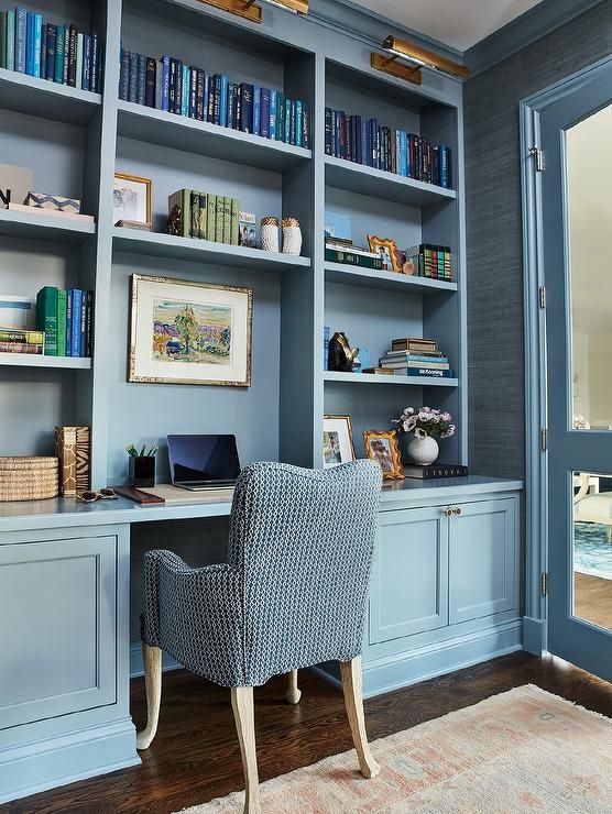 an office with blue bookcases and a chair in front of the desk is full of books