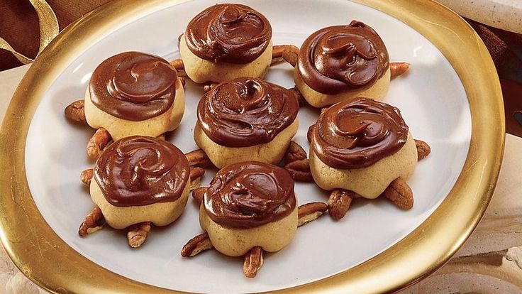 a white plate topped with mini cupcakes covered in chocolate frosting and nuts