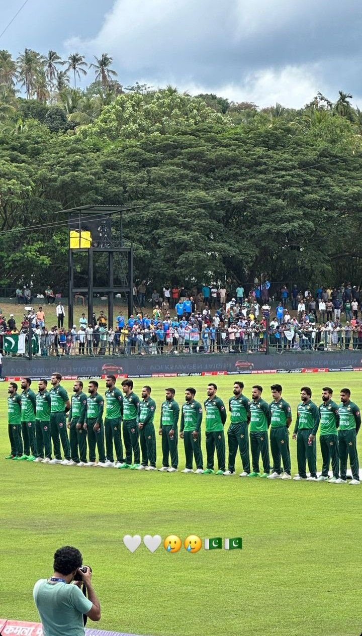 a group of men standing on top of a lush green field next to each other