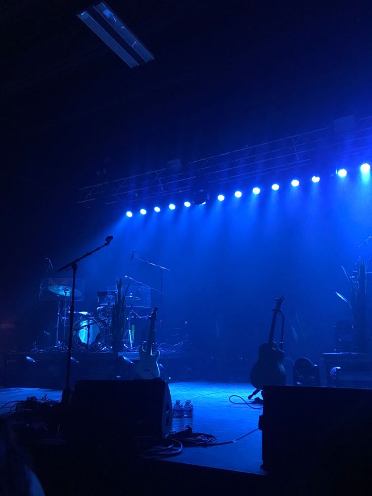 the stage is lit up with blue lights and musical instruments on it's sides