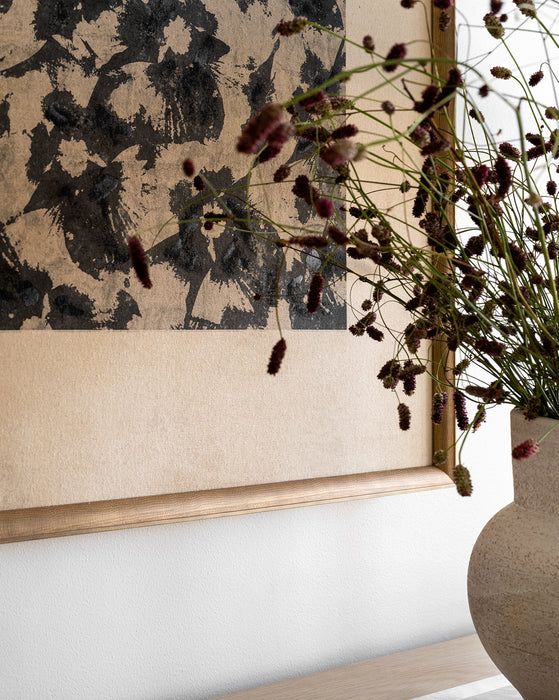 a vase filled with flowers sitting on top of a table next to a framed painting