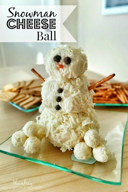 a snowman cheese ball sitting on top of a glass plate next to crackers