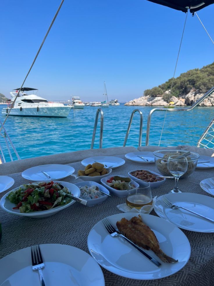 the table is full of food and wine on the boat