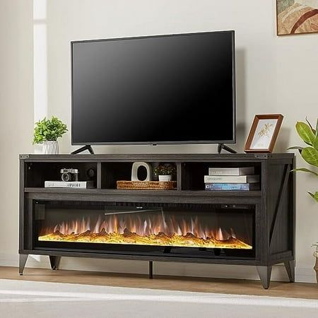 an entertainment center with a flat screen tv and fire flames in the fireplace, next to a potted plant