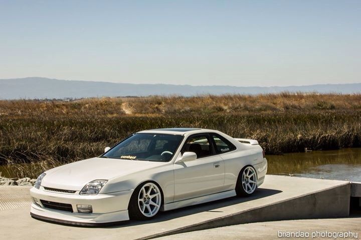 a white car parked on top of a cement slab next to a body of water